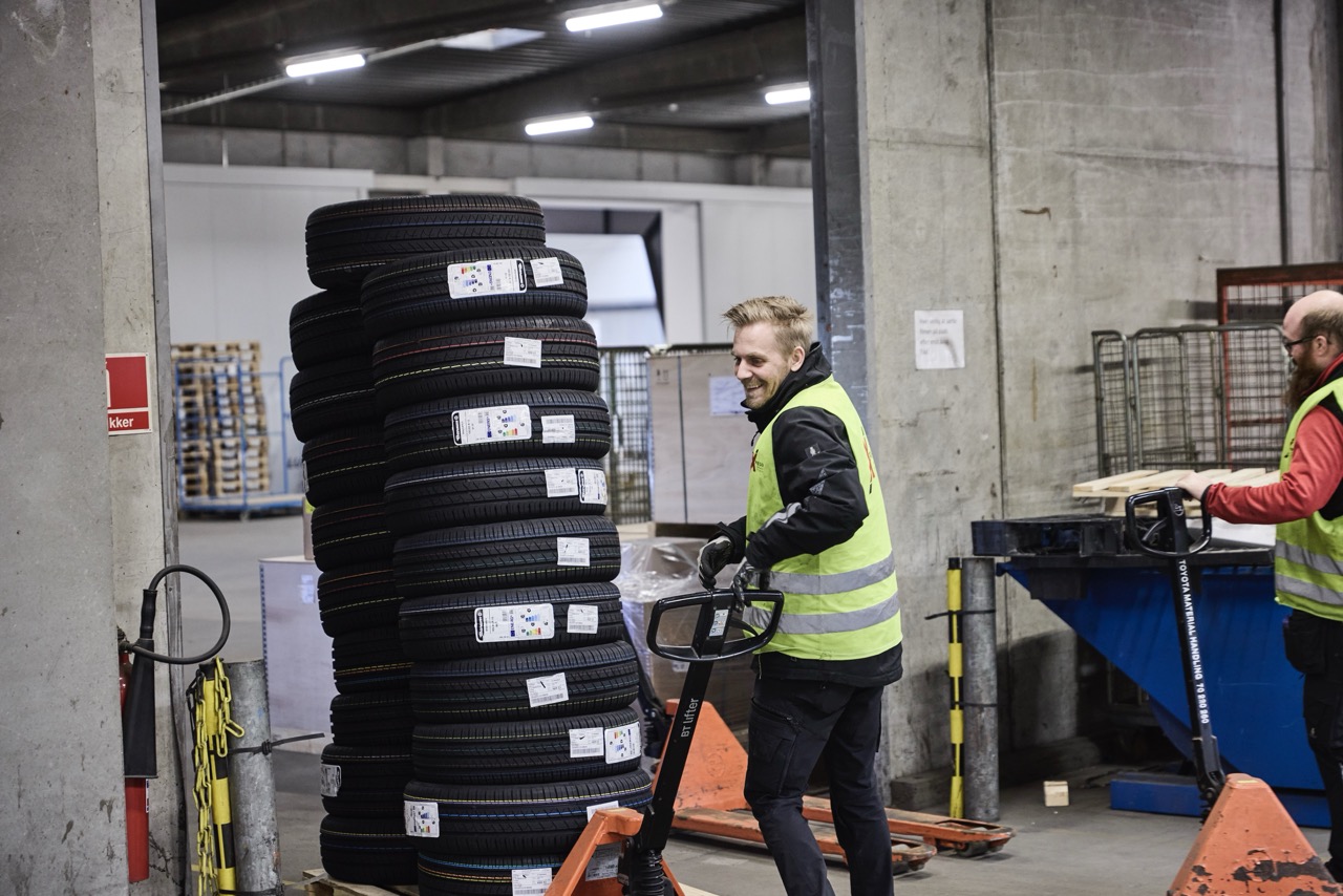 Medarbejder flytter palle med dæk på lageret